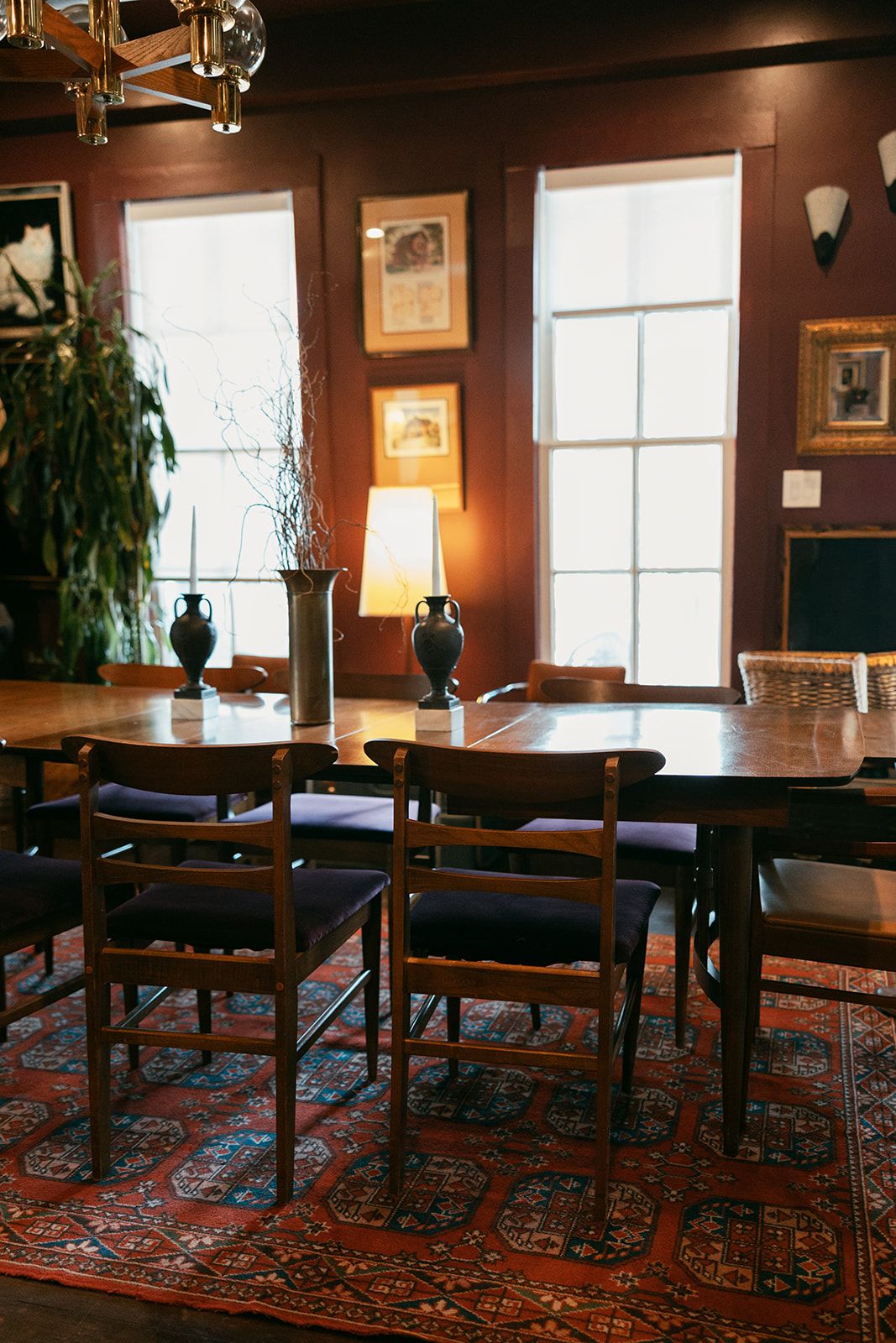 An empty dining room table in front of tall windows