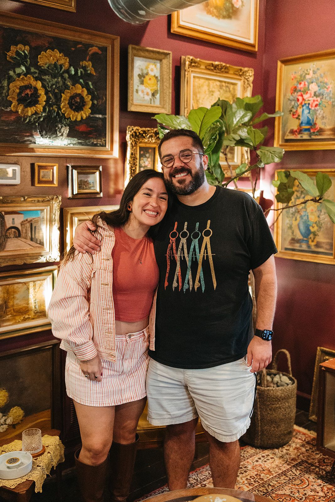 A couple posing together in front of a wall of gold frames