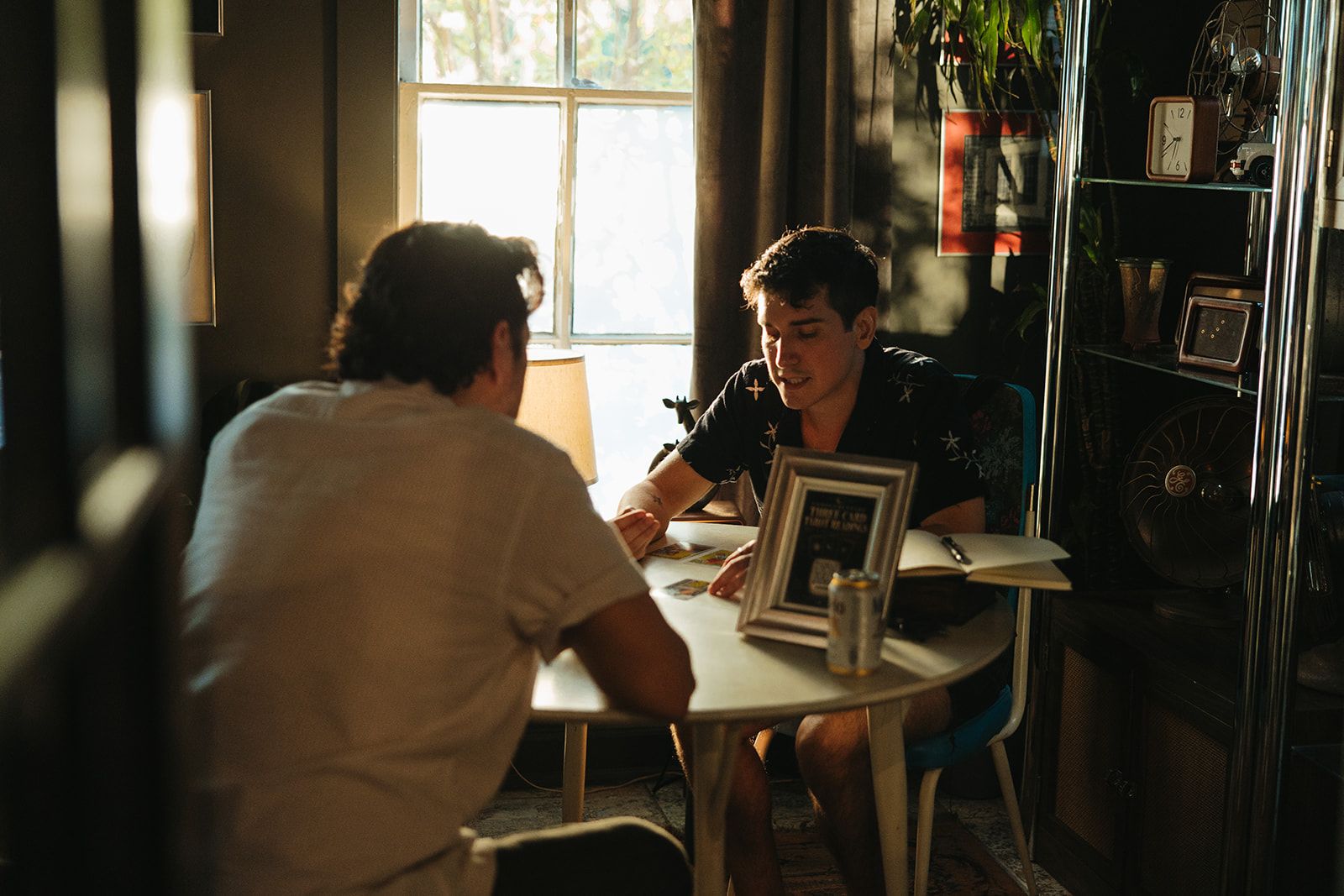 Two people in conversation at a round table by a bright window