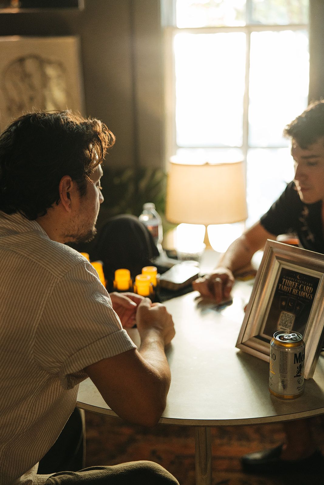 Two people talking at a round table by a sunny window