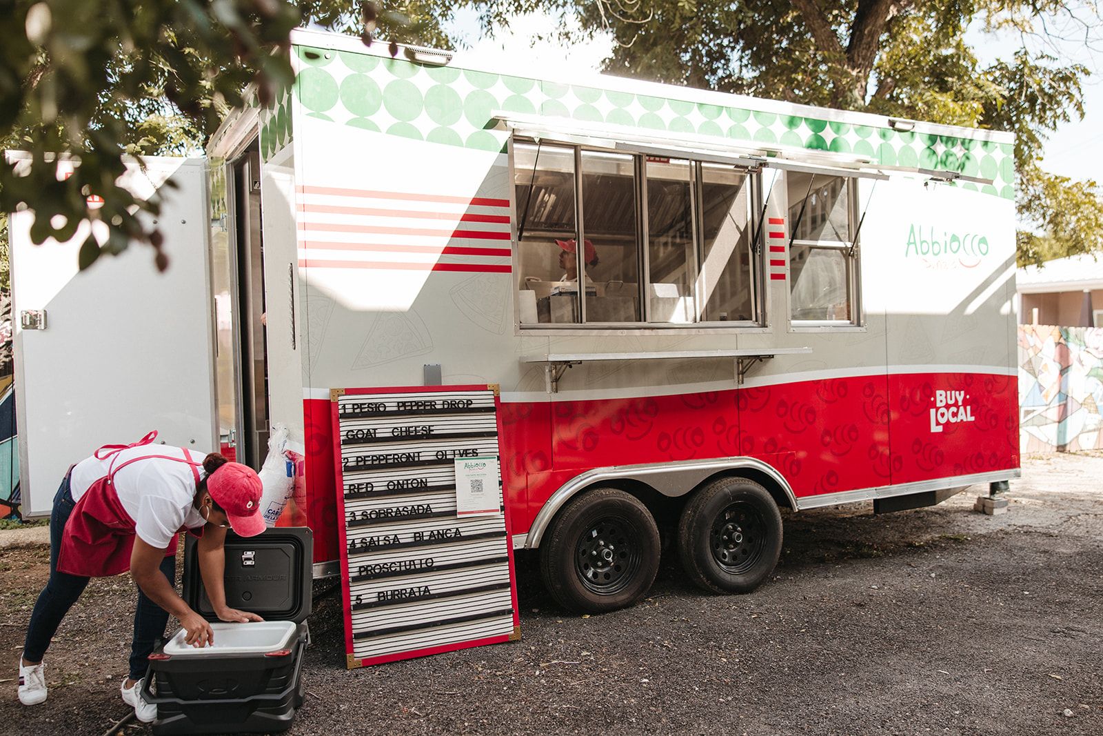A food trailer parked in the yard with a vendor setting up