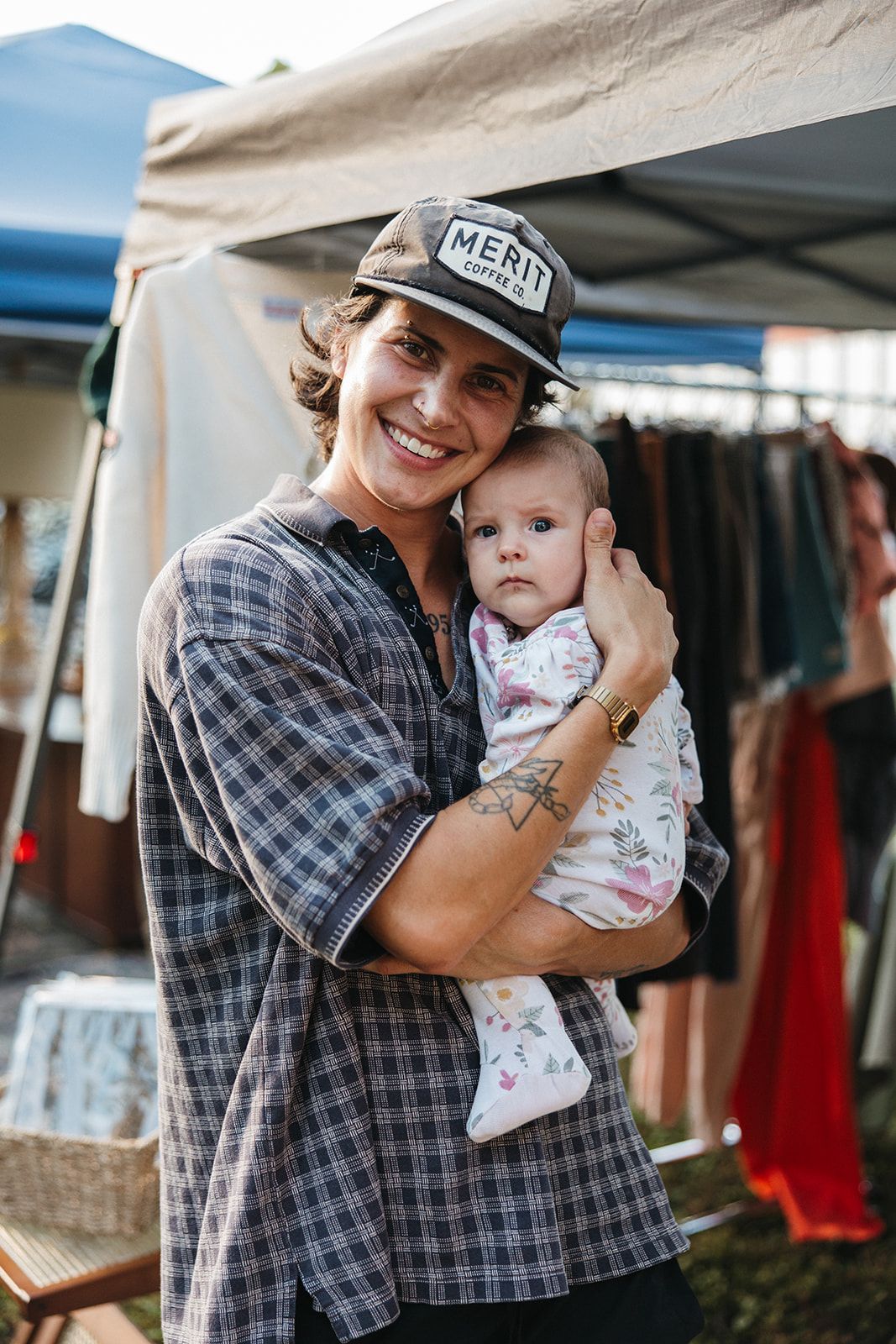 A dad holding a baby while browsing a market booth