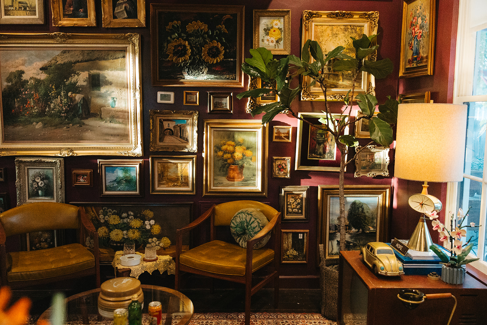 The salon at The Gallery on Montana: a full gallery wall of gilded frames and two mustard leather chairs